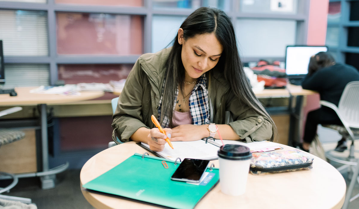 Estudiante mujer escribiendo sobre escritorio