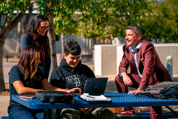 Student and staff seated at outdoor table