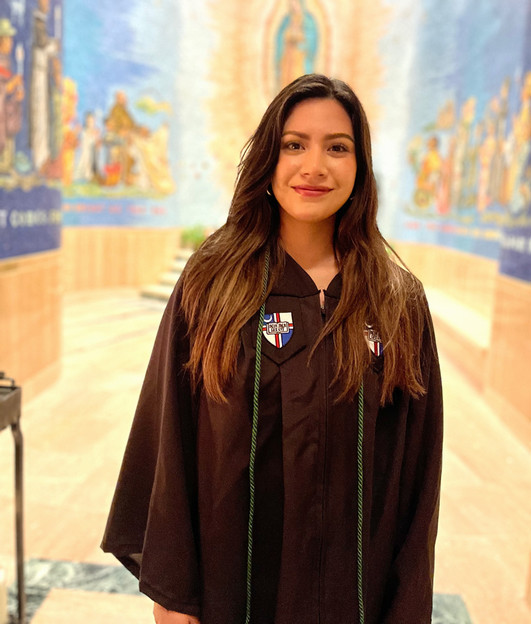 student in graduation gown in front of chapel